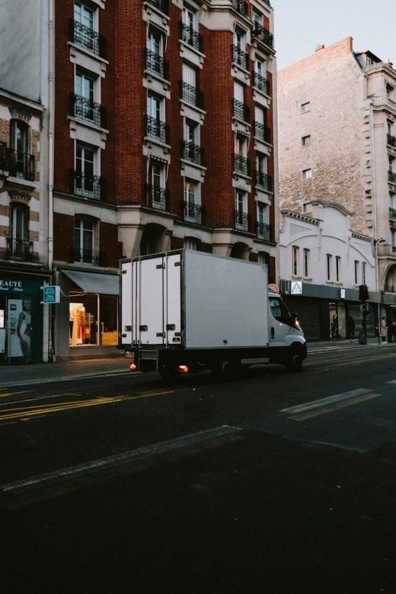 a delivery truck driving down a street next to tall buildings