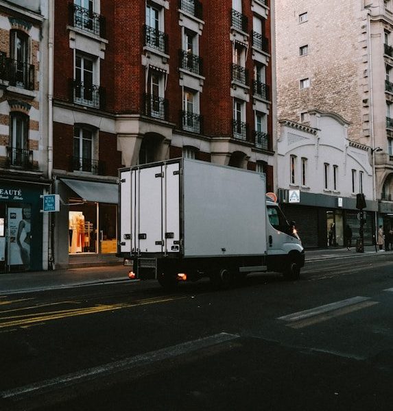 a delivery truck driving down a street next to tall buildings
