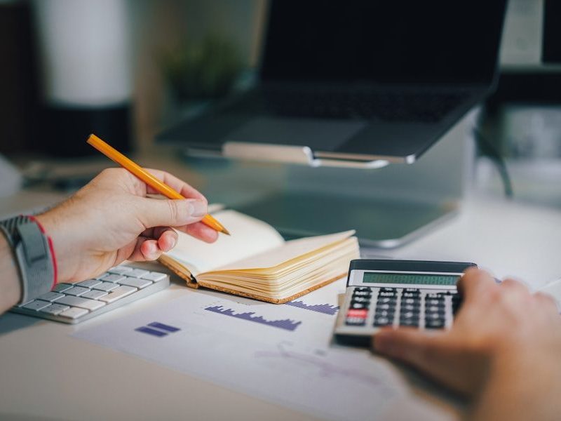 a person sitting at a desk with a calculator and a notebook