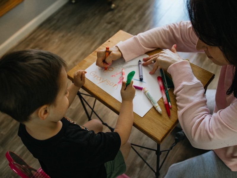 boy in white long sleeve shirt writing on white paper