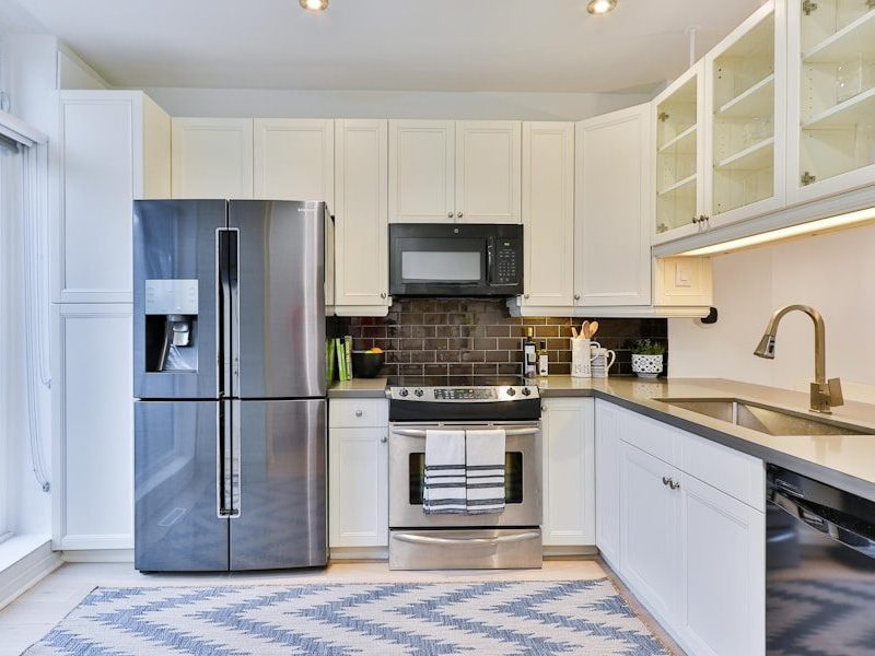 silver french door refrigerator beside white wooden kitchen cabinet