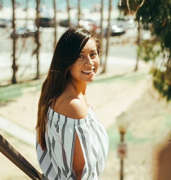 smiling woman standing beside handrails during daytime