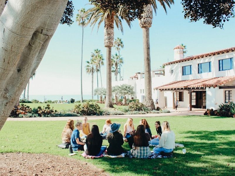 people sitting on ground while forming round during daytime