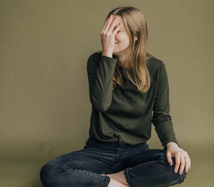woman in black long sleeve shirt and blue denim jeans sitting on brown wooden chair