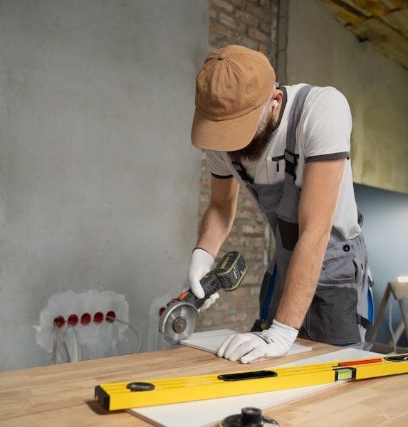 A man sanding a wooden table with a sander