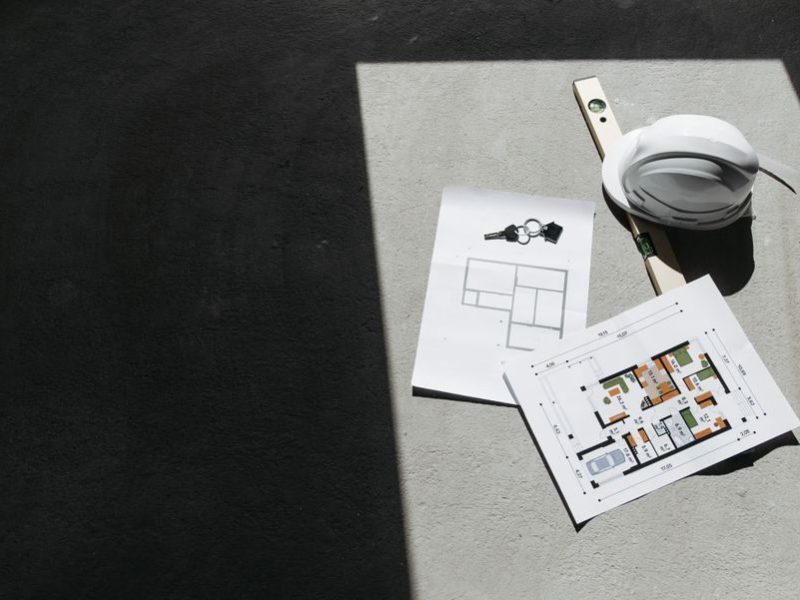 Sunlit construction plans and hard hat on site. Perfect for architecture or building project themes.