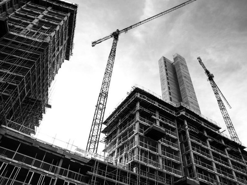 grayscale photo of crane in front of building