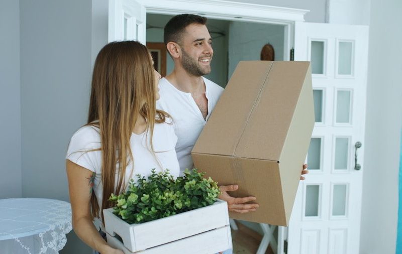 Couple carrying moving boxes into a new home