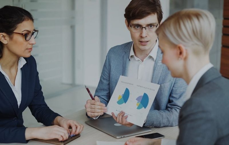 Three professionals discussing charts in a meeting.