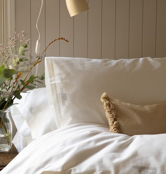 a bed with a white comforter and pillows