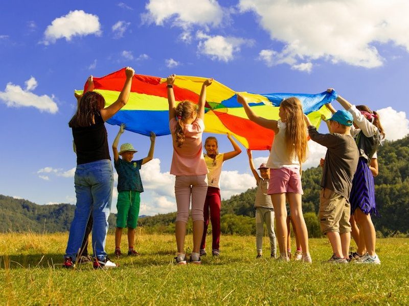 children playing with colorful parachute on grass