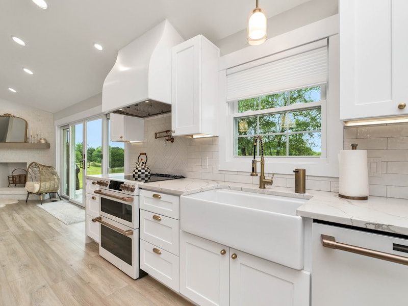 a kitchen with white cabinets and a large window