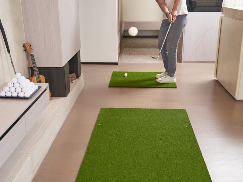 Person practicing golf indoors with putting mats.