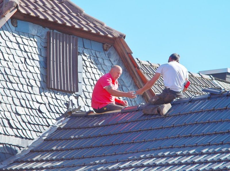 two men working on the roof of a house