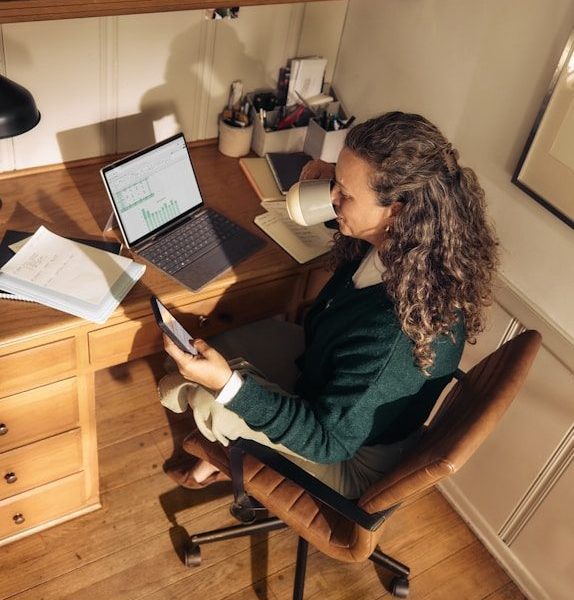 Woman working at a desk with laptop and tablet.