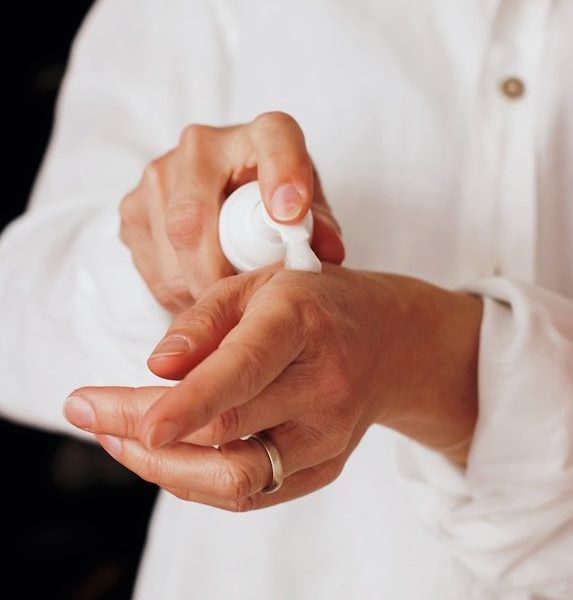 hands applying lotion from white pump