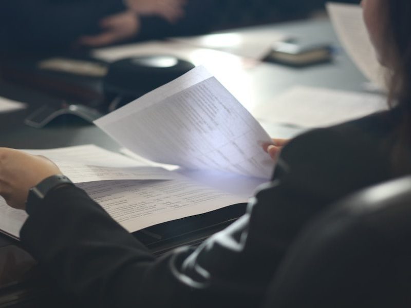 a woman sitting at a table reading a paper