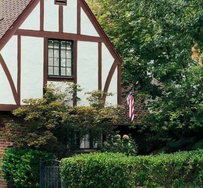 A charming tudor-style house with lush green trees.