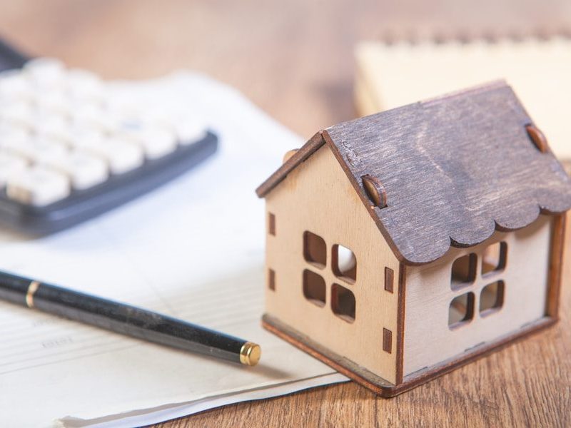 Model house with calculator and pen on desk.