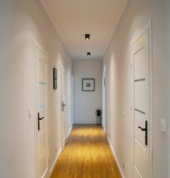 a long hallway with white walls and wooden floors