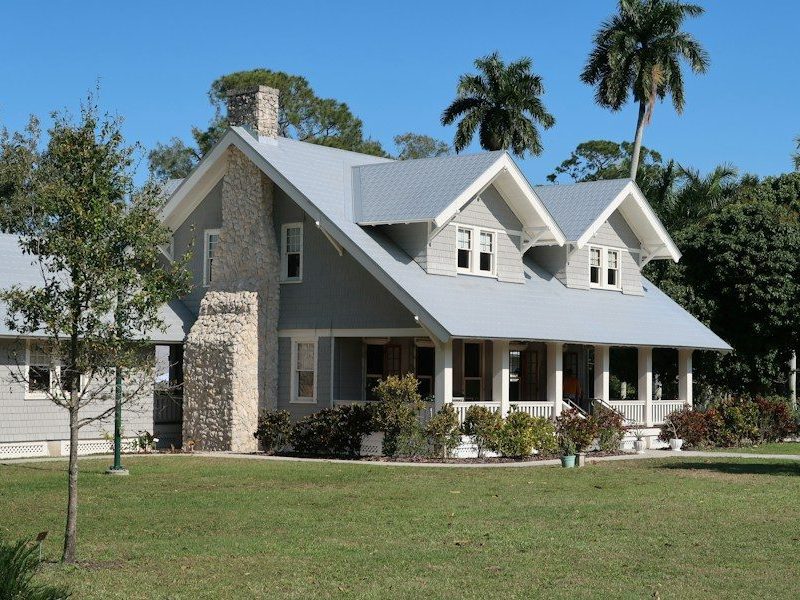 A grey house with a stone chimney and porch in Fort Myers, Florida