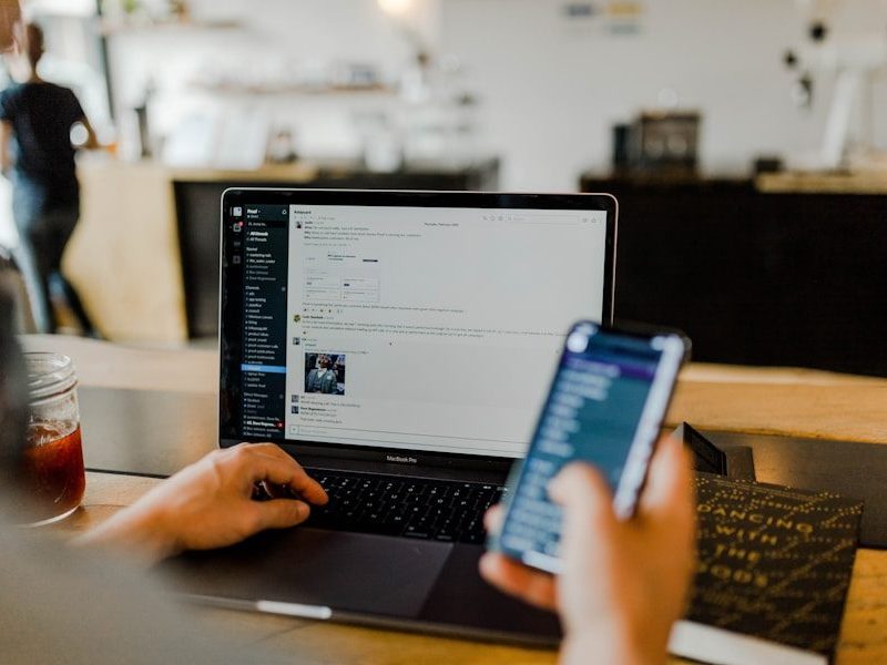 person using phone and laptop