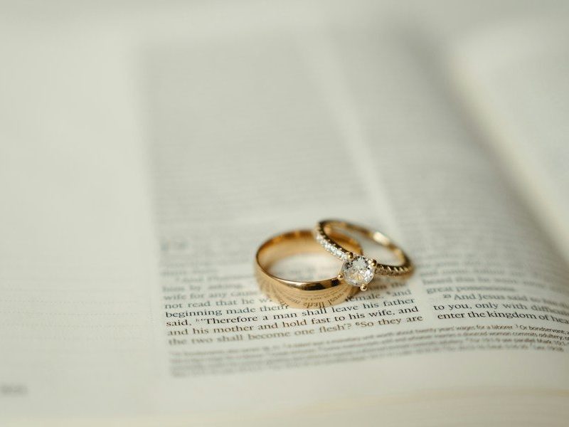 Two gold wedding rings sitting on top of an open book