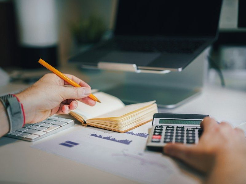 a person sitting at a desk with a calculator and a notebook