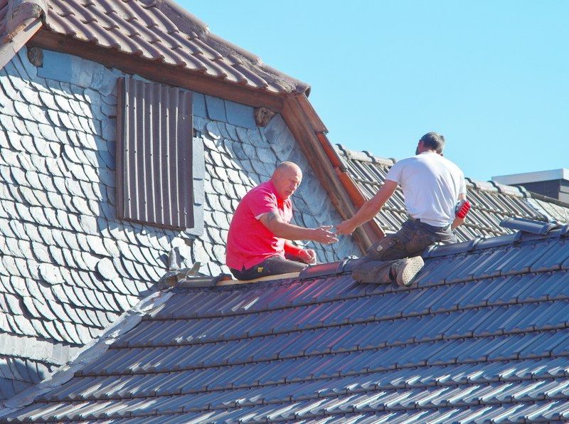 two men working on the roof of a house