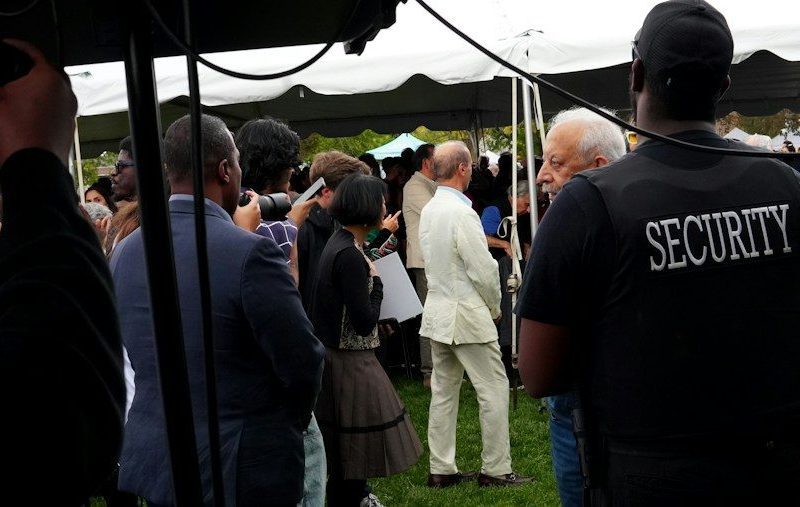 Security guard watches over a gathering under a tent